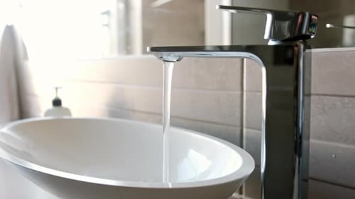 Water Running from Silver Faucet into White Sink