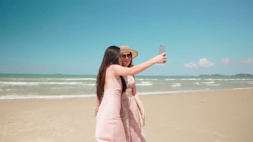 Zwei Frauen machen am Sommertag Selfie-Video am Strand mit einem Smartphone Zwei Frauen machen am Sommertag Selfie-Video am Strand mit einem Smartphone