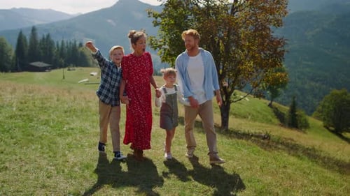 Happy family hiking on sunny mountain hill enjoying beautiful nature views
