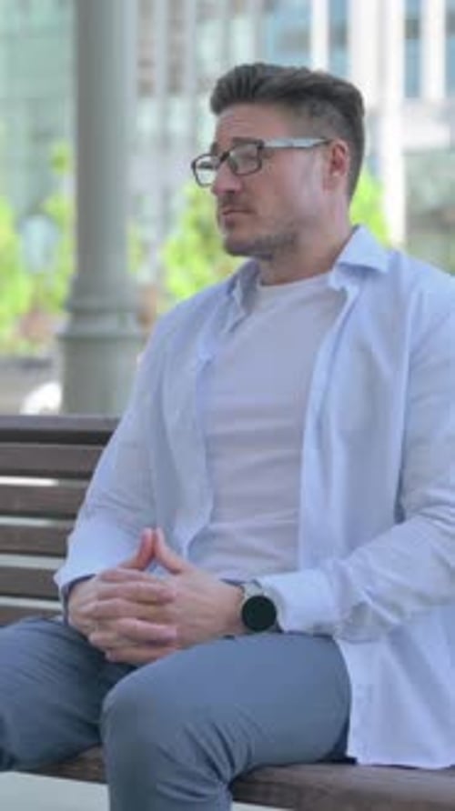 Man Waiting on Park Bench Looking at Watch