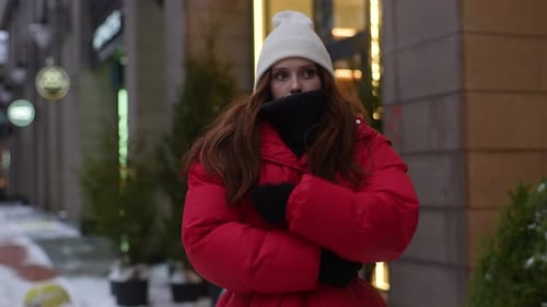 Medium Shot of Frozen Pretty Woman in Winter Outwear Waiting Taxi at City Street in Cold Windy