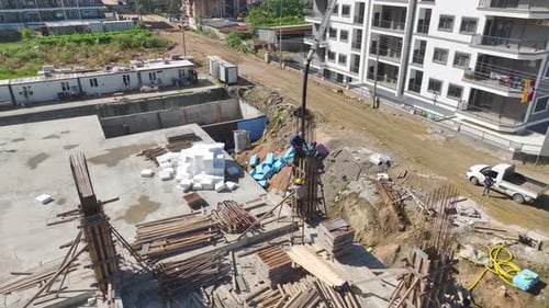 Vista aérea: los trabajadores dan forma a barras de refuerzo y vierten cimientos de concreto