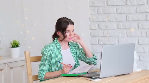 Woman Sitting at a Table Working at a Laptop Computer Concept of Remote Work From Home Home Office