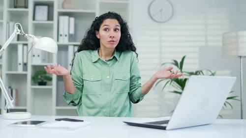 Frustrated Woman Gesturing at Laptop in Bright Office