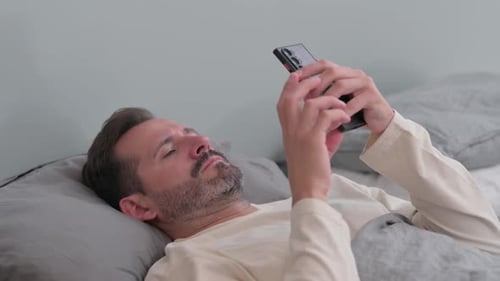 Man Lying in Bed Using Mobile Phone