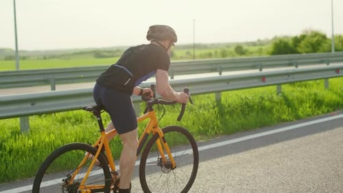 Triathlete Cycling on Bike Along Highway