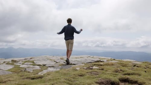 Adolescent atteignant le sommet de la montagne en levant les bras