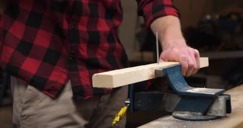 Close up of young carpenter using hammer to hammer the nail into wood plank for build diy wood furni