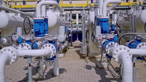 Industrial gas pipeline station with valves, tanks and metal pipes in bright daylight