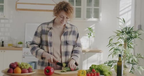 Woman Cuts Cucumber for Healthy Meal in Kitchen