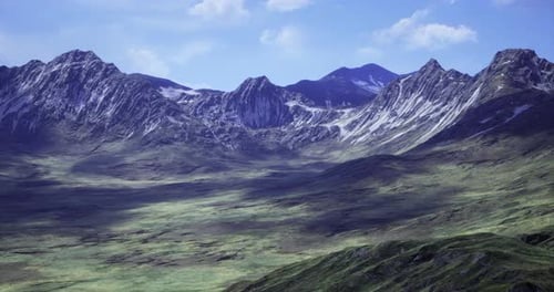 Majestic Mountain Range Under Bright Blue Skies Viewed From a Lush Valley