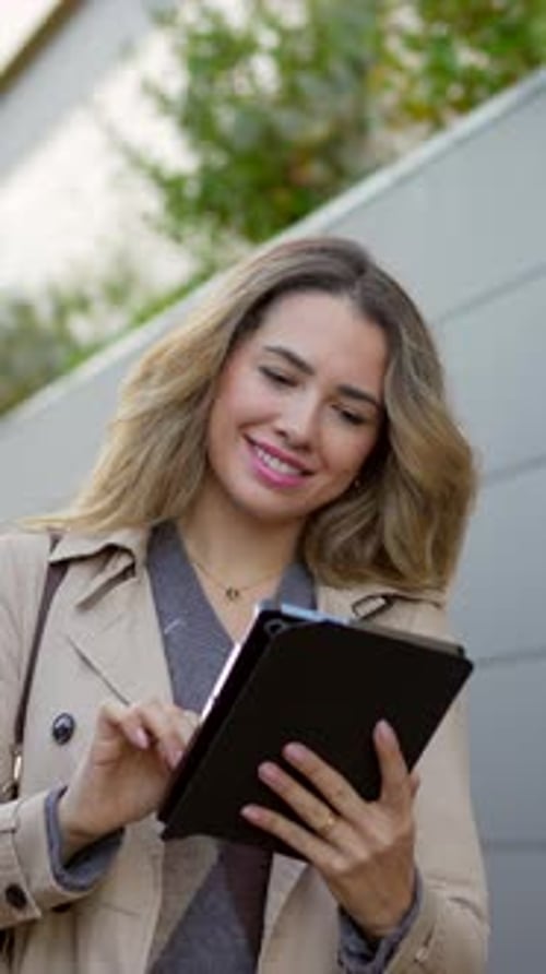 Woman Uses Tablet Device on Street, Smiles