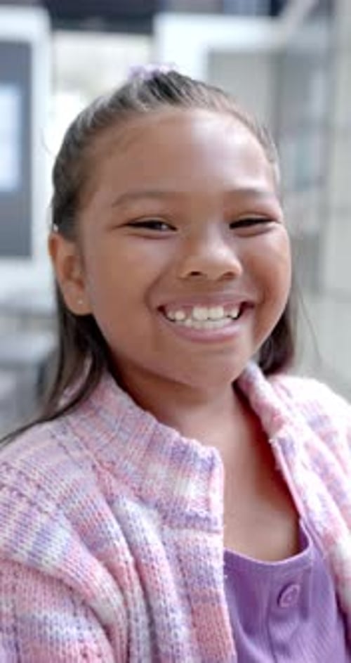 Vidéo verticale : À l'école, une jeune fille biraciale au sourire éclatant est debout