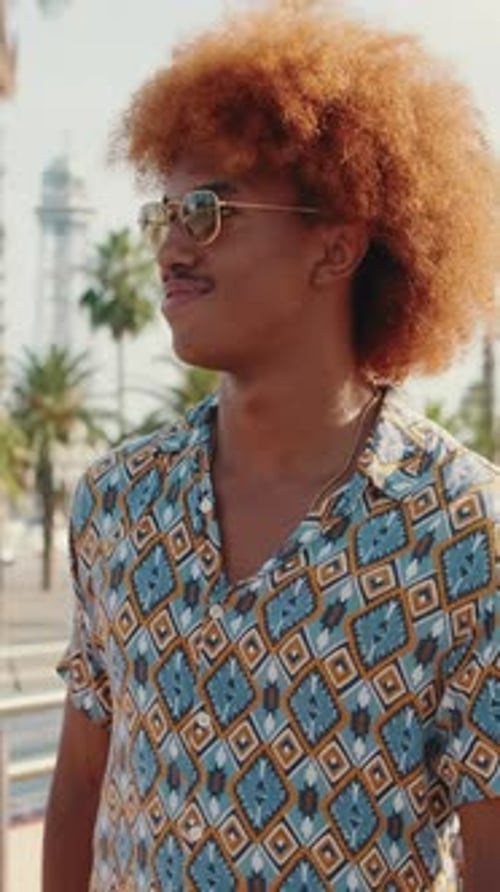 Smiling young man with curly hair walks in city