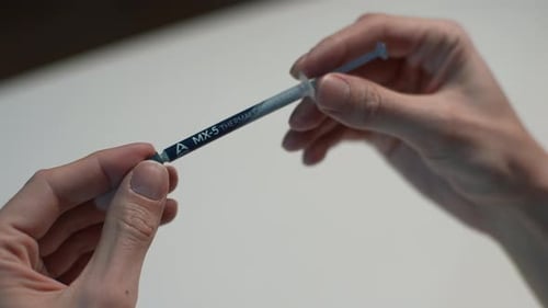 Hands Hold Syringe of Thermal Compound