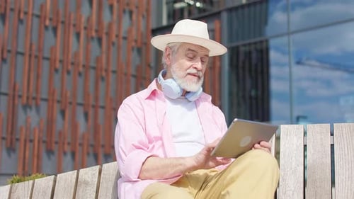Senior Man Using Tablet Outdoors on Bench