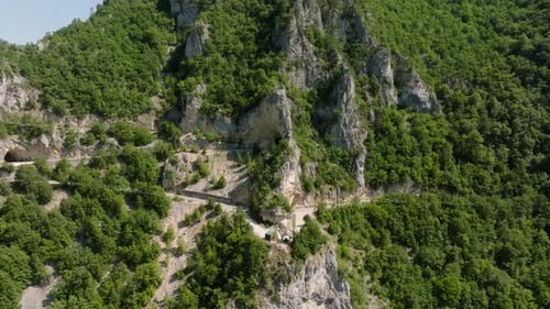 Luftaufnahme beim Wegfahren von einer Aussichtsplattform und einer kurvenreichen Straße mit Bögen in den Bergen,