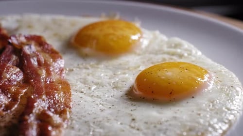 Cooked Eggs And Bacon In A Plate Ready To Eat. close up, slider shot