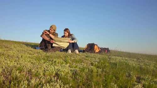 Couple Planning Hiking Trip on a Grassy Hill