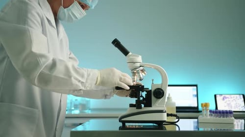 Dedicated Scientist Working with Microscope in Bright Lab