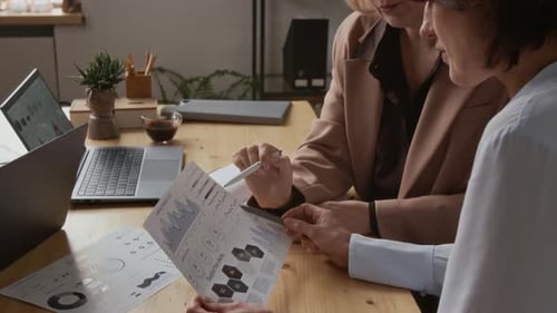 Two Professional Middle-Aged Businesswomen Discussing Documents in Modern Office