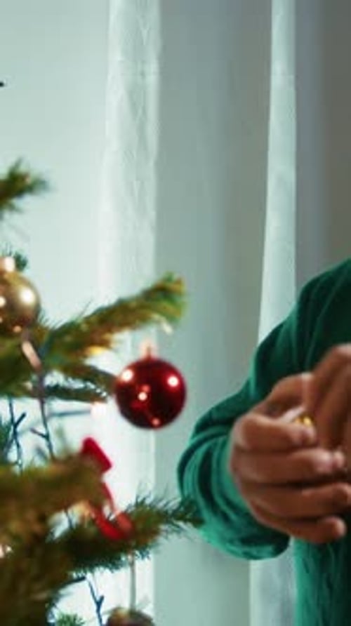 Person Decorating Christmas Tree with Ornaments