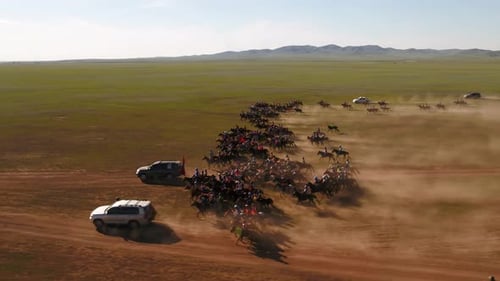 Cinematic Drone shot of a group of jockeys riding in a fast canter and gallop over the Mongolian ste
