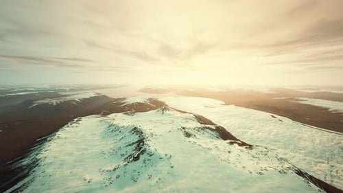 Aerial Flyover of Golden Hour Snow-Capped Mountains and Valleys