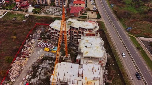 Construction site with a crane and nearby buildings in aerial view