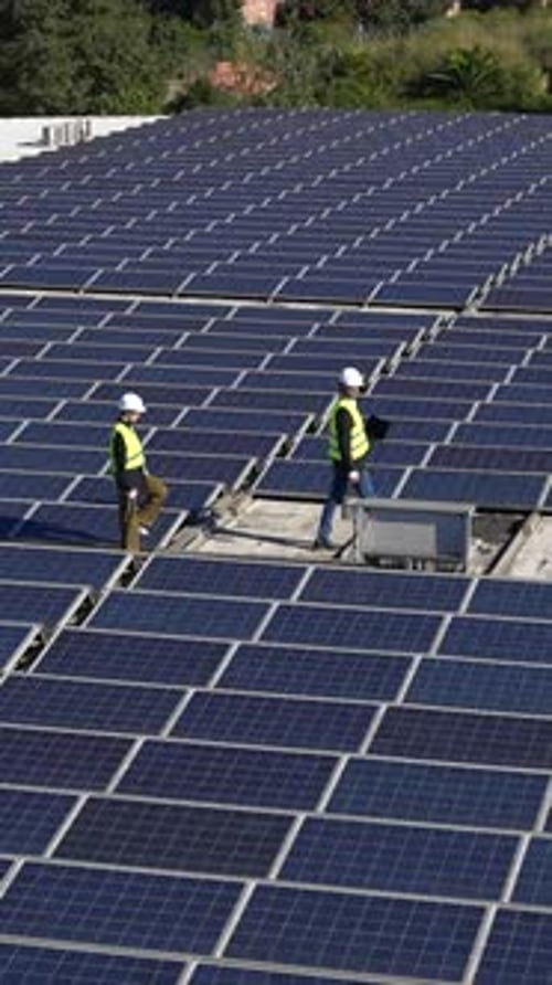 Ingenieure inspizieren eine große Solarpanelanlage auf einem Dach
