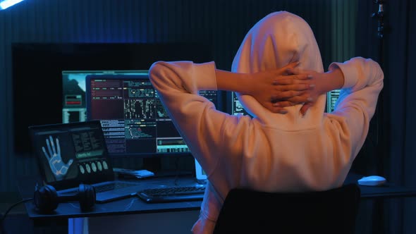 With hands behind the neck. Young professional female hacker is indoors ...