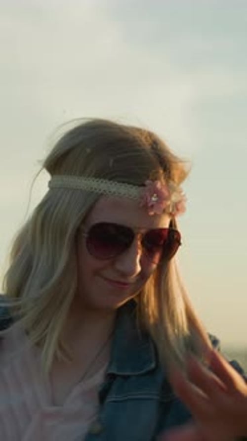 Carefree Woman Dancing with Joy in Sunglasses and Floral Headband