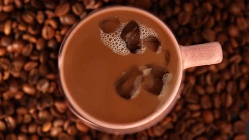 Top View Cup of Iced Coffee on Coffee Bean Background