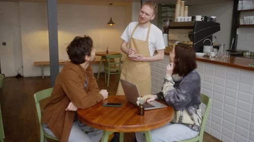 Couple in Cafe Ordering from Waiter