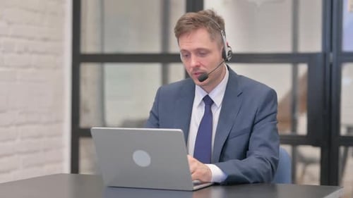 Young Businessman with Headset Talking Online with Customer in Call Center