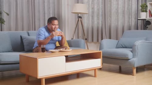 Man Eating Burger at Home on the Couch