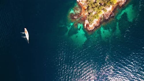 Aerial view of the big expedition sailing boat moving in the calm sea near the tropical island