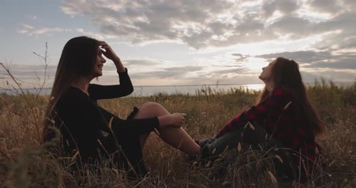 Woman Friends Talking and Speaking Together Sitting on a Hill