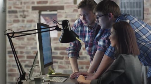 Equipe de jovens funcionários está discutindo um projeto de trabalho na tela do computador.