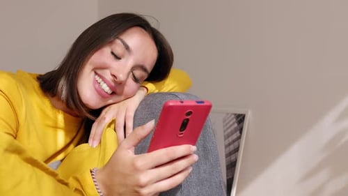 Portrait of Young Beautiful Woman Using Mobile Phone Relaxing on Sofa at Home