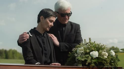 Mourning Couple Standing Next to Coffin