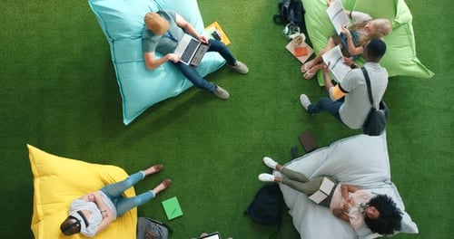 Students using technology and sitting on bean bags in a library from above
