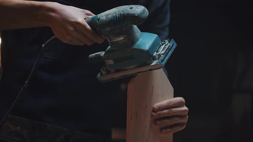Side View of a Carpenters Hands with a Grinder A Young Apprentice Guy Works in a Carpentry Workshop