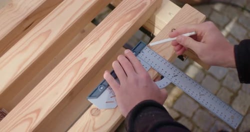 Hands Measuring Wood with Ruler and Pencil