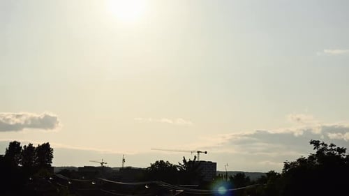 Timelapse of sunset over city with few clouds in the sky and orange teal tones.