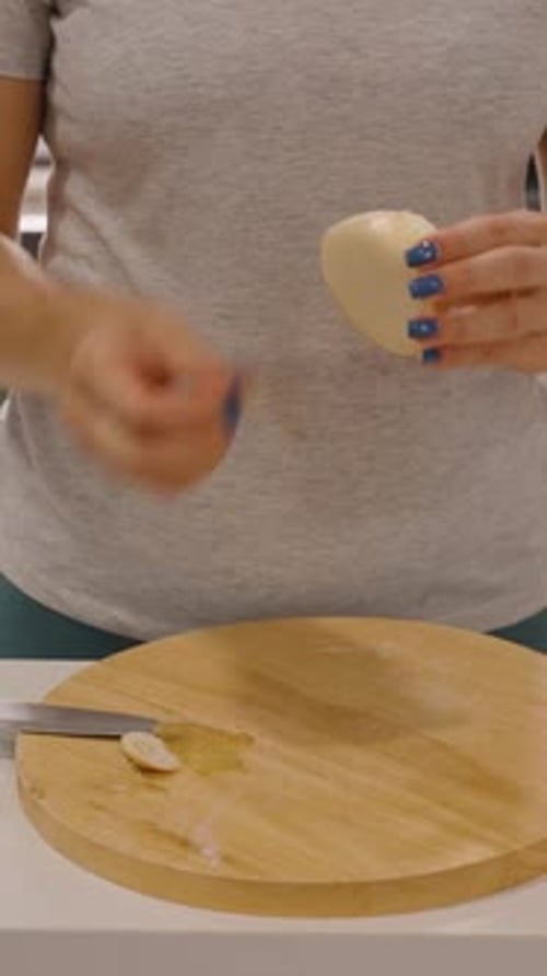Vertical video. Woman Peeling Onion with Knife on Round Board in Modern Kitchen, Medium Angle, Meal