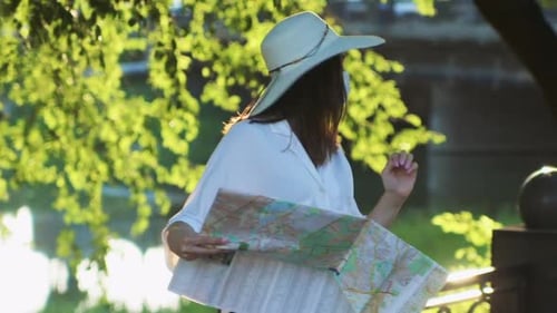 Woman in Hat Looks at Map Outdoors