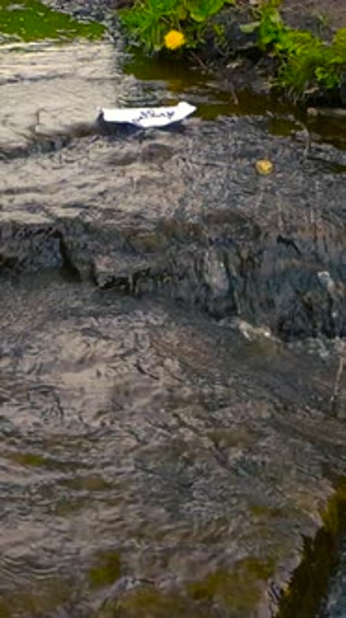 Paper Letter with the Word Goodbye Floating Away on a Stream