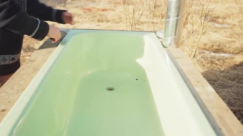 Der Mann steckt einen Stopfen ein und füllt den DIY-Whirlpool mit Wasser — Nahaufnahme