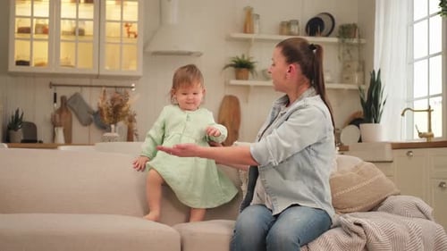 Happy Infant Walking on Sofa with Adult Guidance